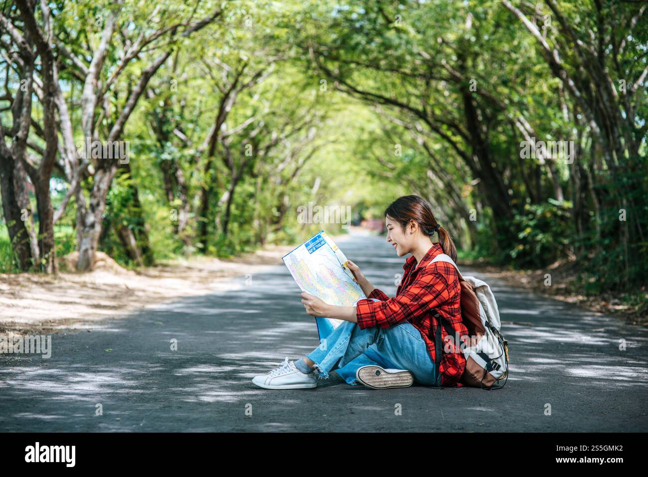 Les touristes féminins s'assoient et regardent la carte sur la route. Banque D'Images