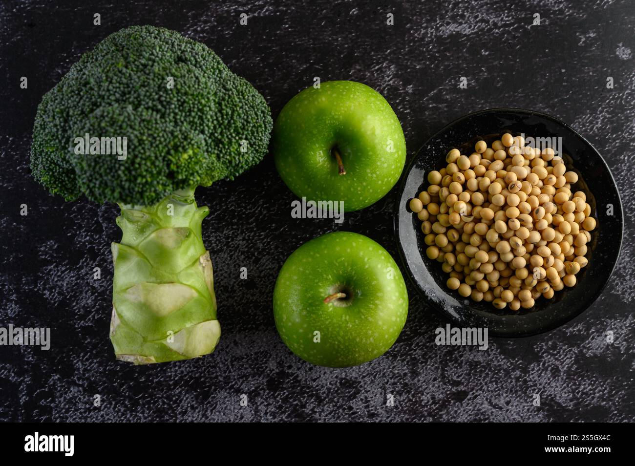Brocoli, pomme et fèves de soja sur un fond de sol en ciment noir. Banque D'Images