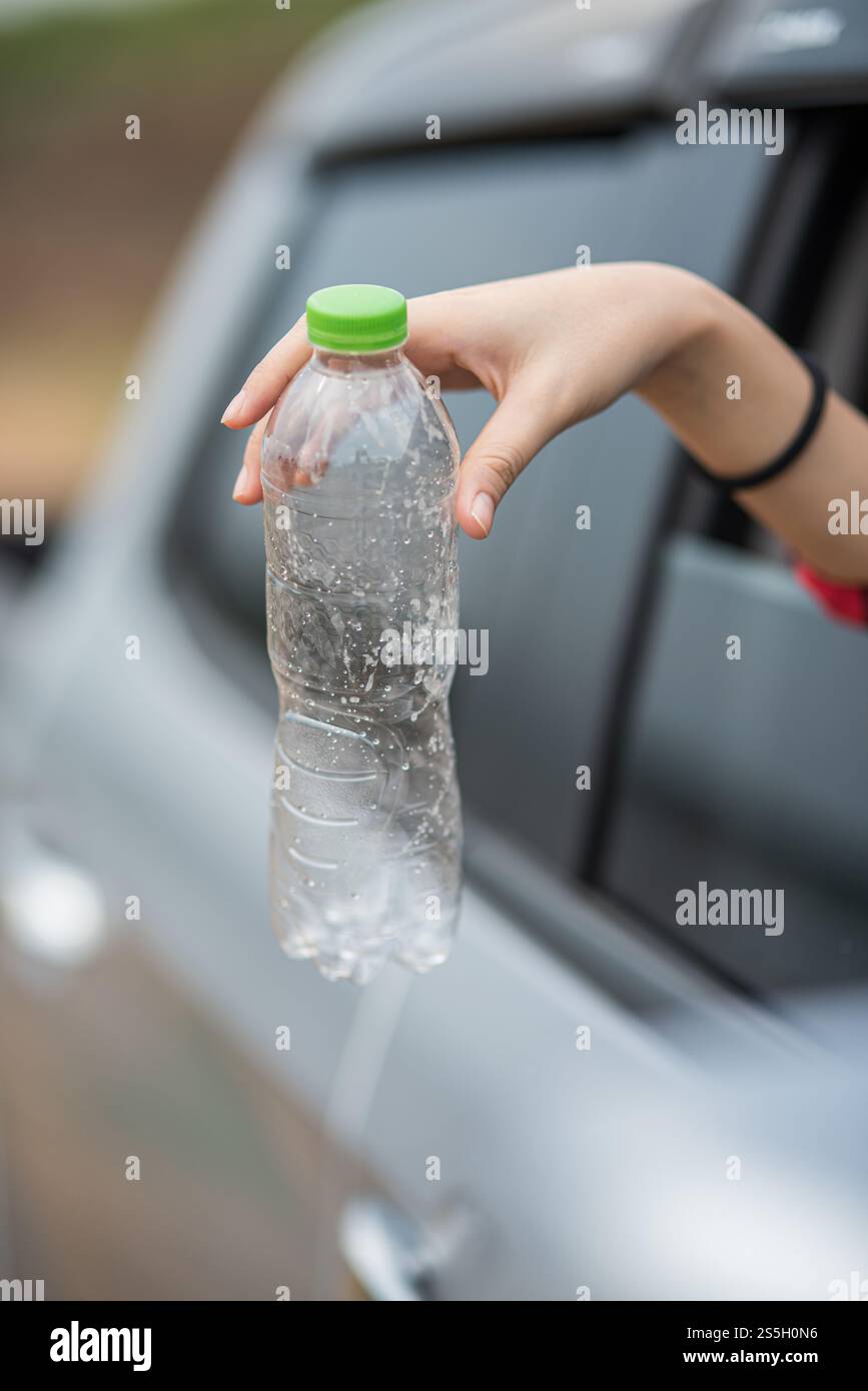 Bras qui tiennent des bouteilles d'eau et se détachent de la voiture. Banque D'Images