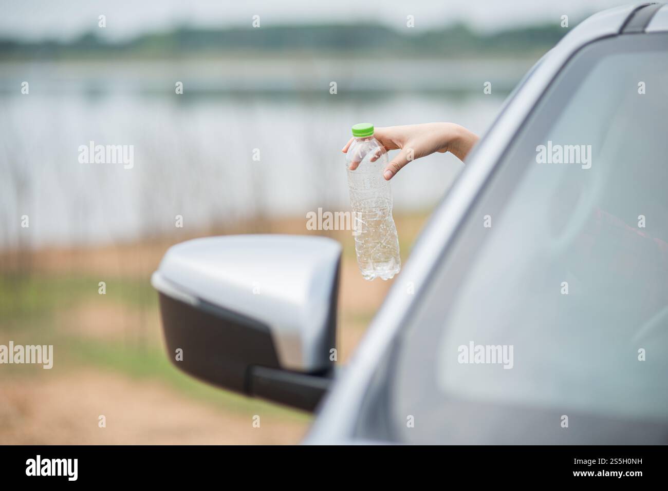 Bras qui tiennent des bouteilles d'eau et se détachent de la voiture. Banque D'Images