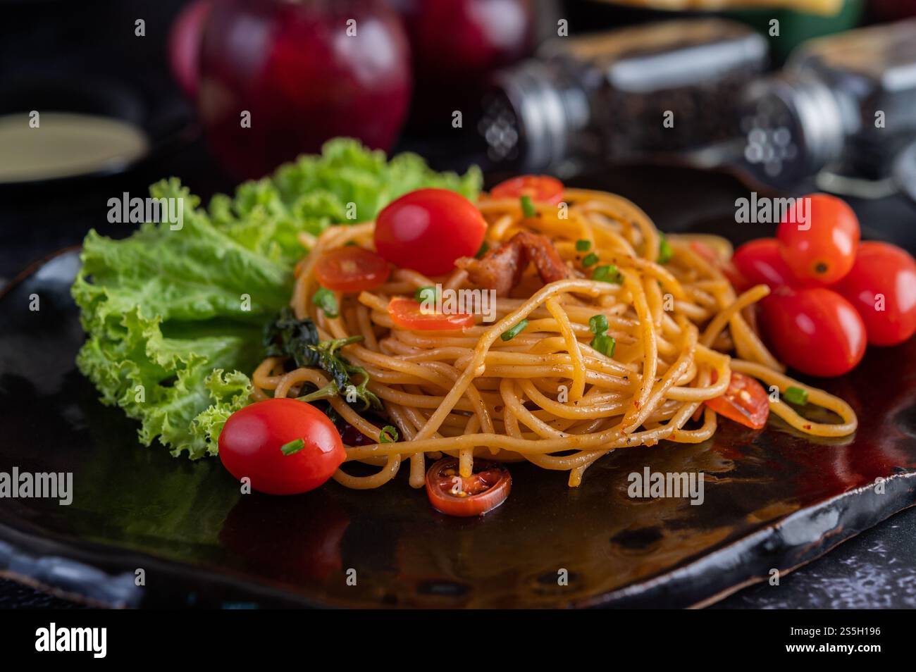 Spaghetti dans une tasse noire avec tomates et laitue. Mise au point sélective. Banque D'Images Spaghetti dans une tasse noire avec tomates et laitue. Mise au point sélective. Banque D'Images