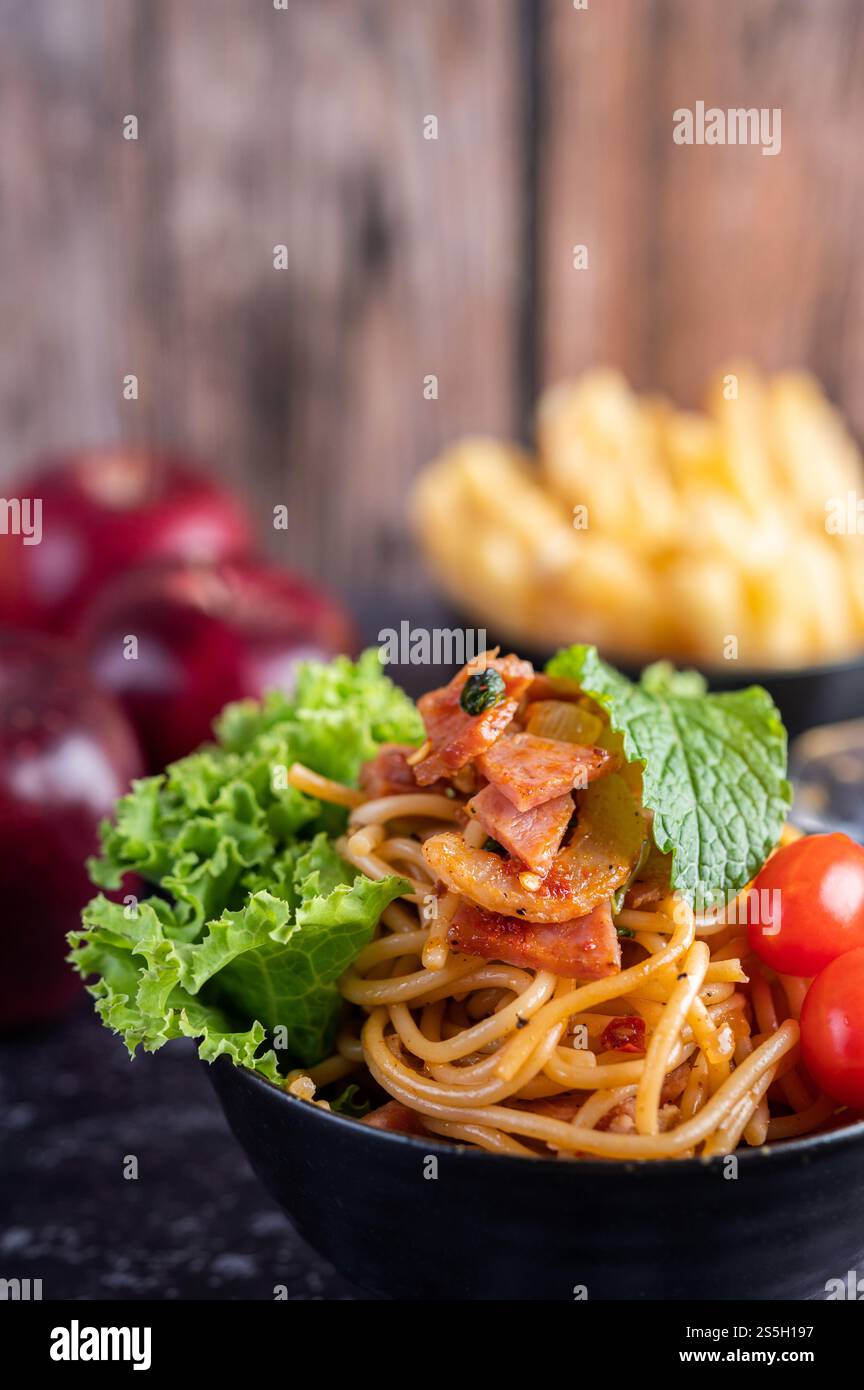Spaghetti dans une tasse noire avec tomates et laitue. Mise au point sélective. Banque D'Images Spaghetti dans une tasse noire avec tomates et laitue. Mise au point sélective. Banque D'Images