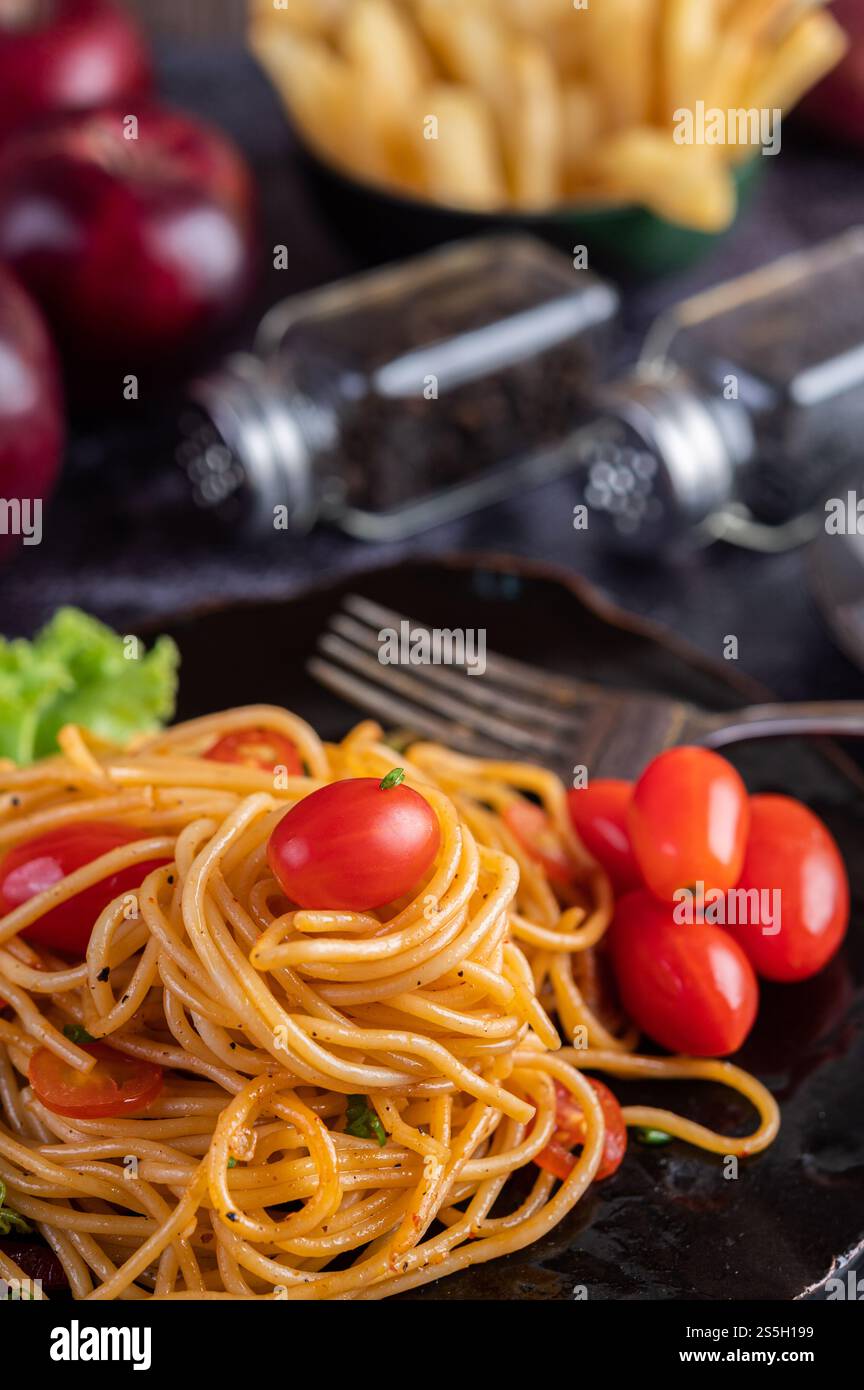 Spaghetti dans une tasse noire avec tomates et laitue. Mise au point sélective. Banque D'Images Spaghetti dans une tasse noire avec tomates et laitue. Mise au point sélective. Banque D'Images