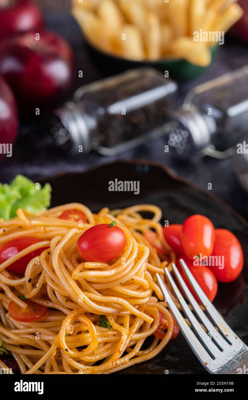 Spaghetti dans une tasse noire avec tomates et laitue. Mise au point sélective. Banque D'Images Spaghetti dans une tasse noire avec tomates et laitue. Mise au point sélective. Banque D'Images
