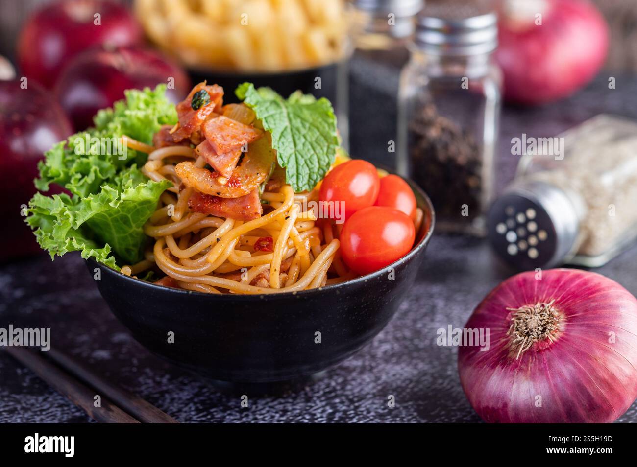 Spaghetti dans une tasse noire avec tomates et laitue. Mise au point sélective. Banque D'Images Spaghetti dans une tasse noire avec tomates et laitue. Mise au point sélective. Banque D'Images
