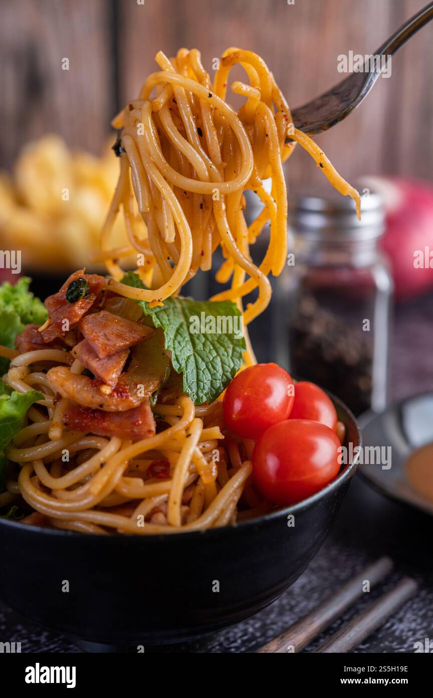 Spaghetti dans une tasse noire avec tomates et laitue. Mise au point sélective. Banque D'Images Spaghetti dans une tasse noire avec tomates et laitue. Mise au point sélective. Banque D'Images