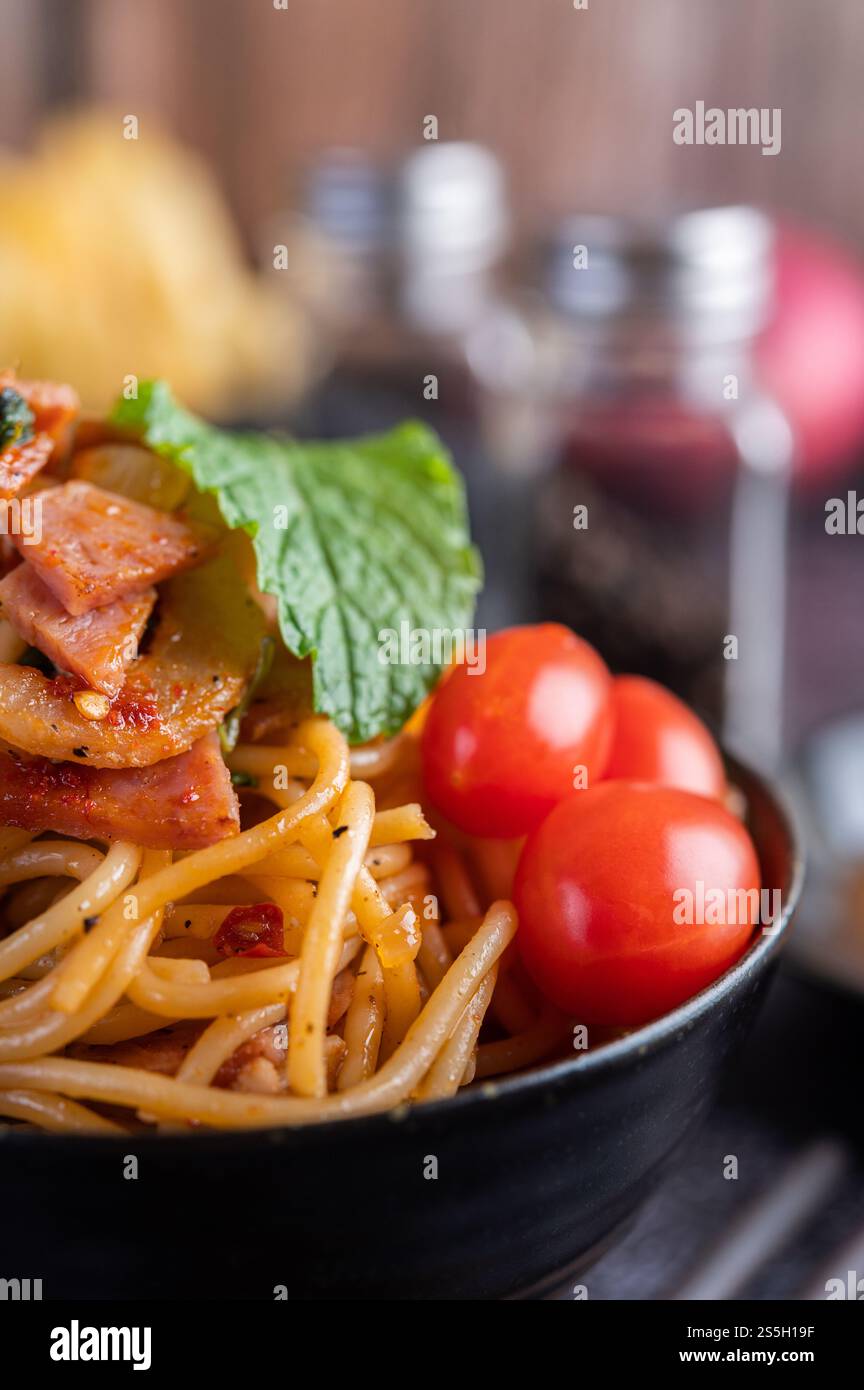 Spaghetti dans une tasse noire avec tomates et laitue. Mise au point sélective. Banque D'Images Spaghetti dans une tasse noire avec tomates et laitue. Mise au point sélective. Banque D'Images