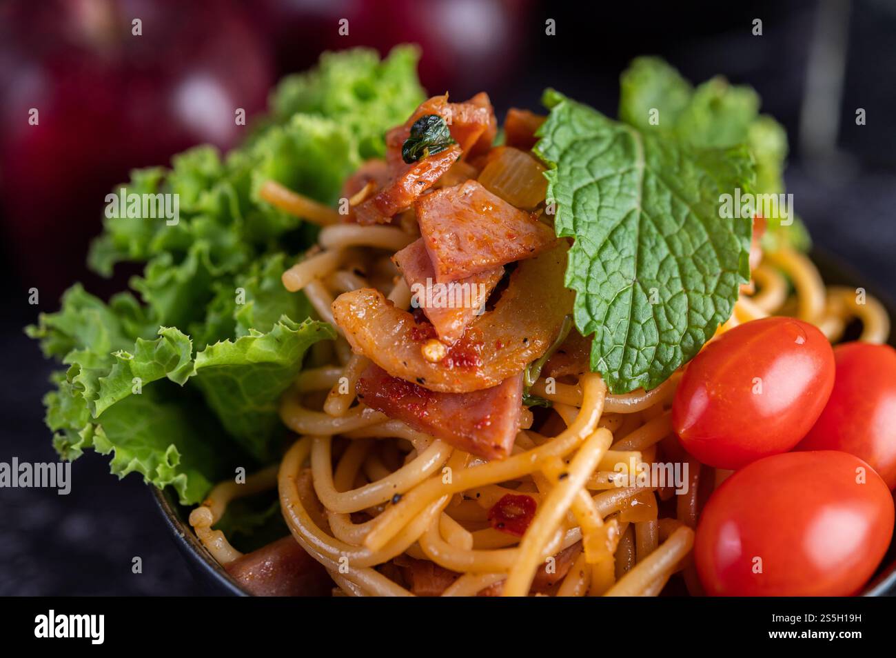 Spaghetti dans une tasse noire avec tomates et laitue. Mise au point sélective. Banque D'Images Spaghetti dans une tasse noire avec tomates et laitue. Mise au point sélective. Banque D'Images