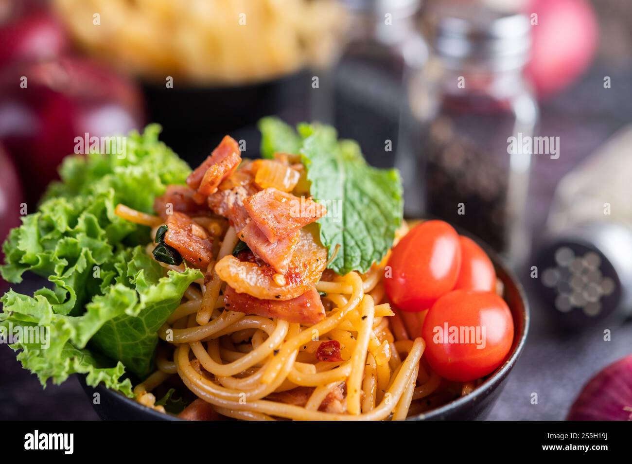 Spaghetti dans une tasse noire avec tomates et laitue. Mise au point sélective. Banque D'Images Spaghetti dans une tasse noire avec tomates et laitue. Mise au point sélective. Banque D'Images