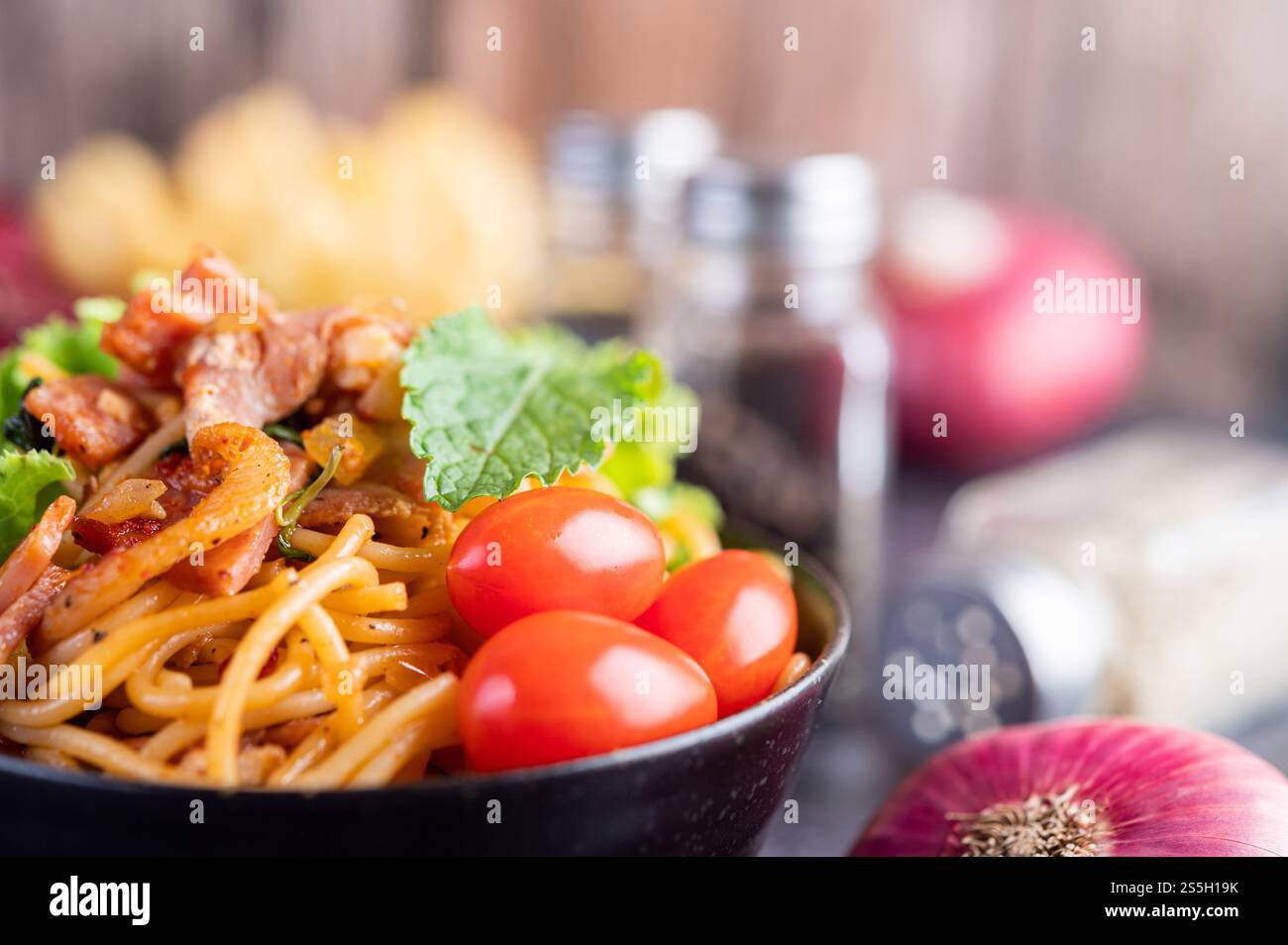 Spaghetti dans une tasse noire avec tomates et laitue. Mise au point sélective. Banque D'Images Spaghetti dans une tasse noire avec tomates et laitue. Mise au point sélective. Banque D'Images
