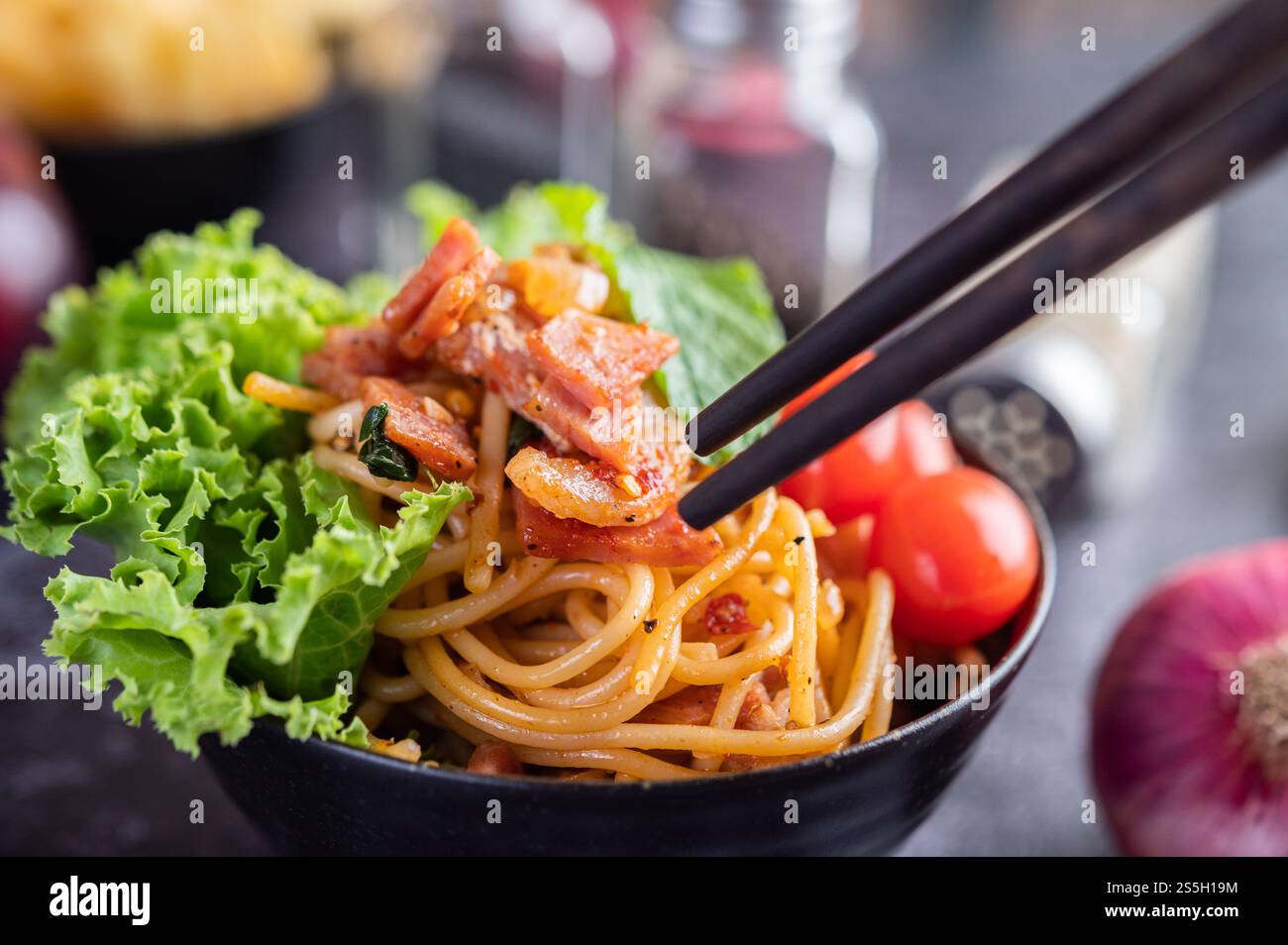 Spaghetti dans une tasse noire avec tomates et laitue. Mise au point sélective. Banque D'Images Spaghetti dans une tasse noire avec tomates et laitue. Mise au point sélective. Banque D'Images