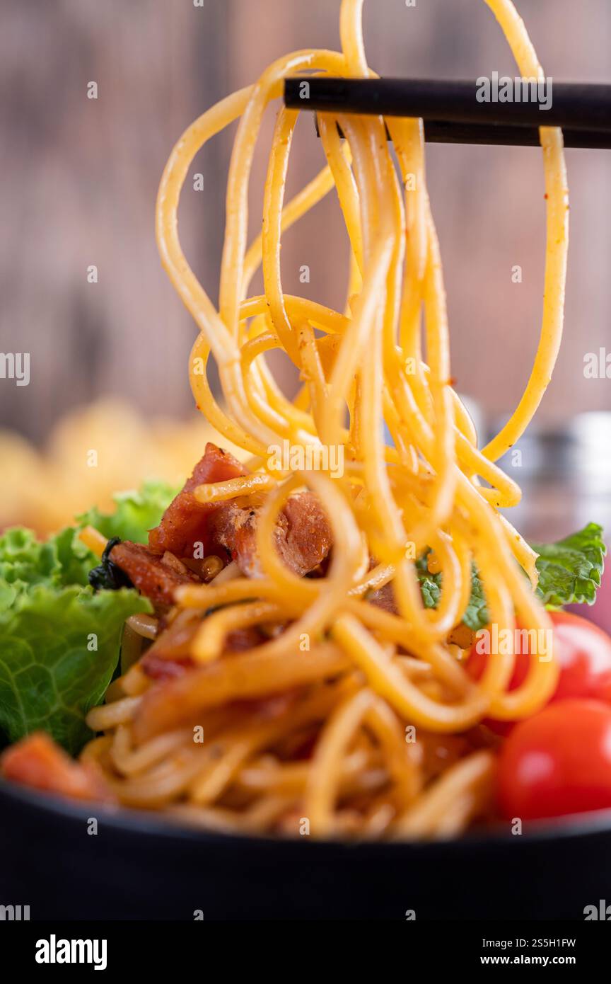 Spaghetti dans une tasse noire avec tomates et laitue. Mise au point sélective. Banque D'Images Spaghetti dans une tasse noire avec tomates et laitue. Mise au point sélective. Banque D'Images