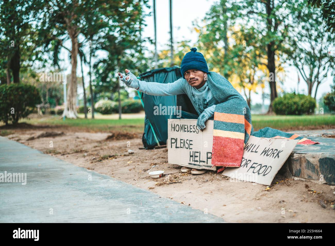 un homme assis mendiants avec des sans-abri s'il vous plaît message d'aide. Mise au point sélective. Banque D'Images