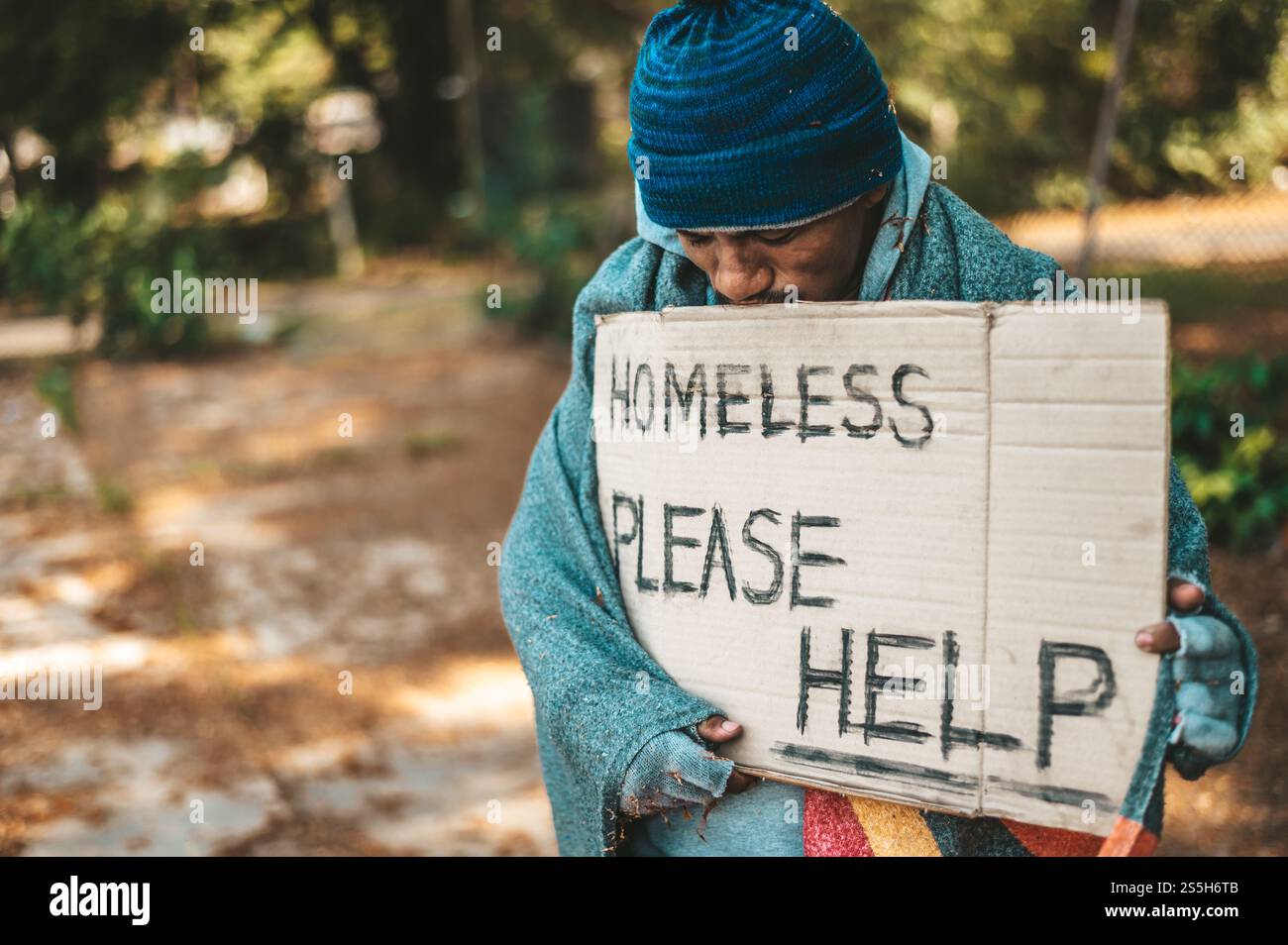Mendiant debout dans la rue avec des messages pour les sans-abri s'il vous plaît aider. Banque D'Images