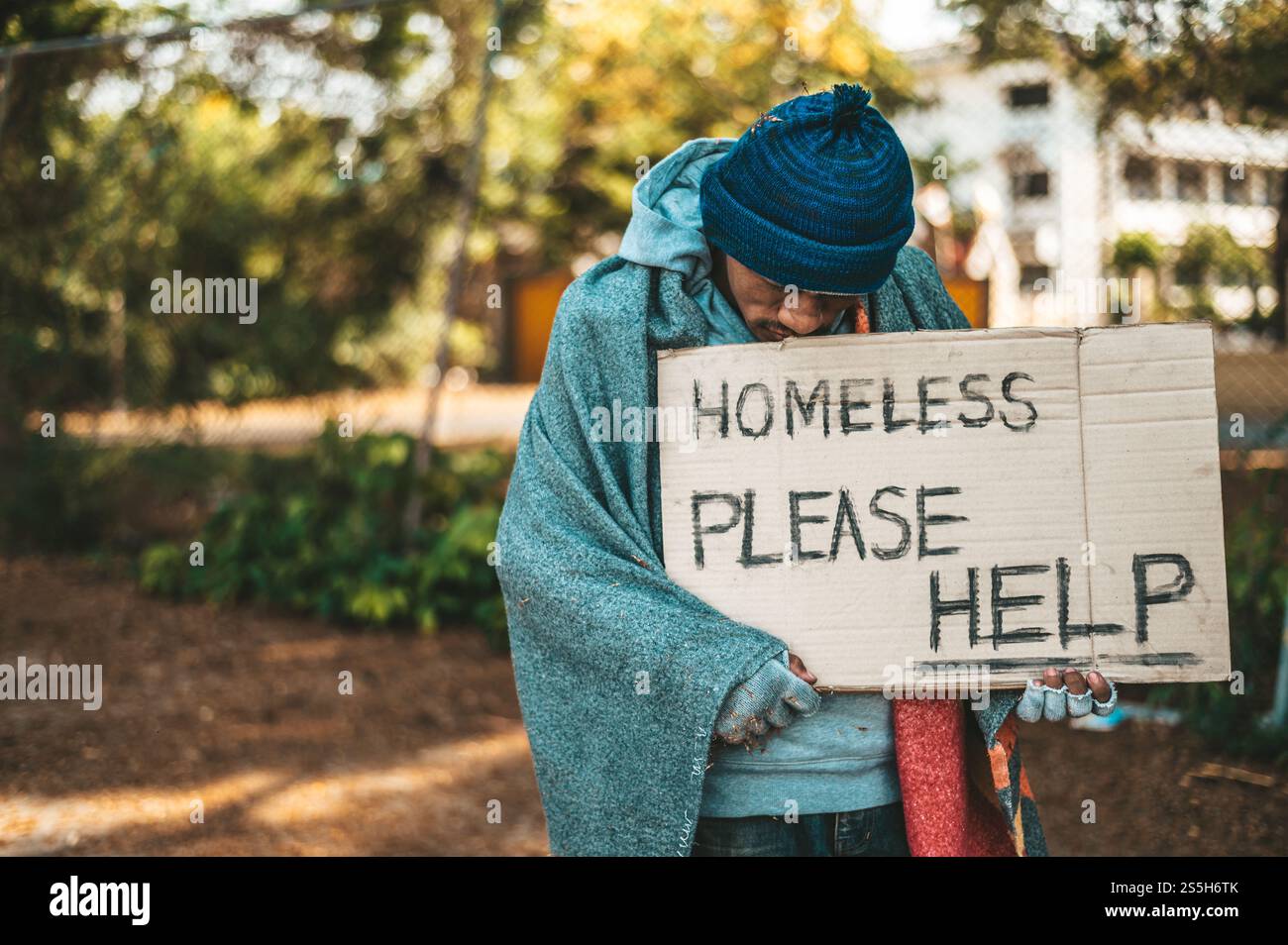 Mendiant debout dans la rue avec des messages pour les sans-abri s'il vous plaît aider. Banque D'Images