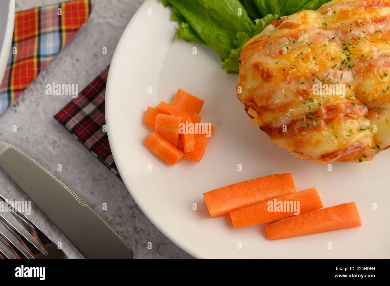 Vue de dessus et gros plan avec pain à la saucisse dans un plat blanc avec carotte, couteau avec fourchette et serviette sur la table, espace de copie Banque D'Images
