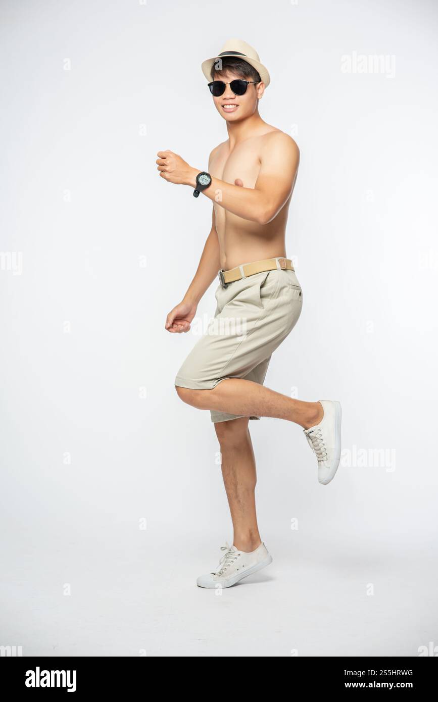 L'homme sans sa chemise sauta sur une jambe et sourit. Banque D'Images