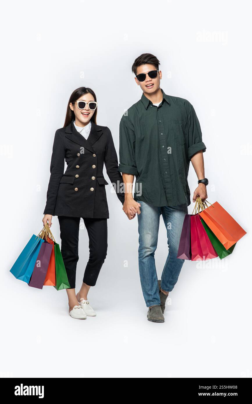 Une paire d'hommes et de femmes portaient des lunettes et transportaient beaucoup de sacs en papier pour faire du shopping. Banque D'Images