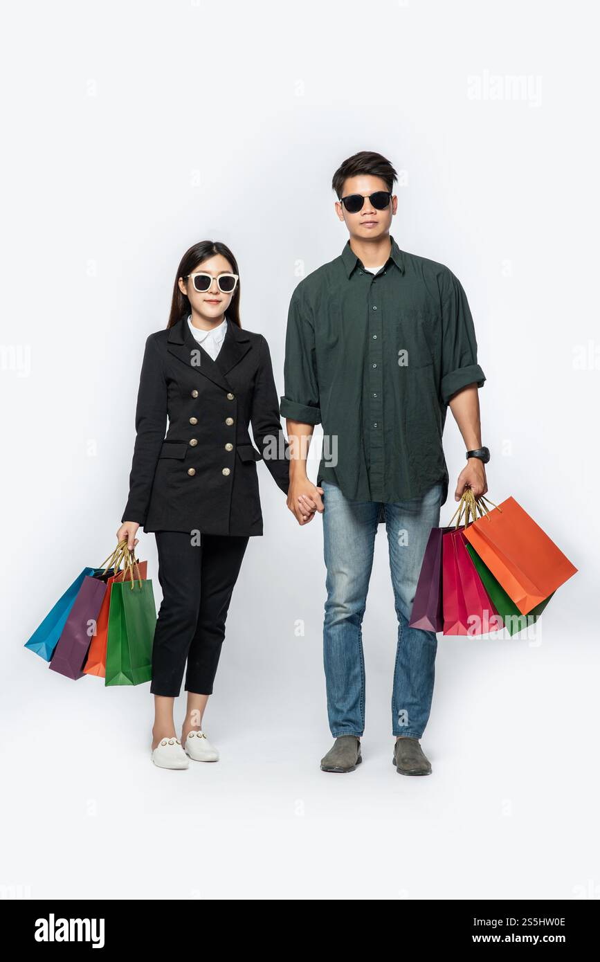 Une paire d'hommes et de femmes portaient des lunettes et transportaient beaucoup de sacs en papier pour faire du shopping. Banque D'Images