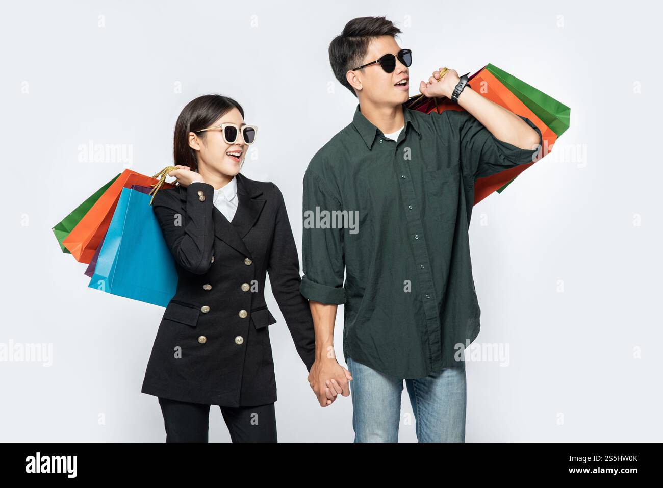 Une paire d'hommes et de femmes portaient des lunettes et transportaient beaucoup de sacs en papier pour faire du shopping. Banque D'Images