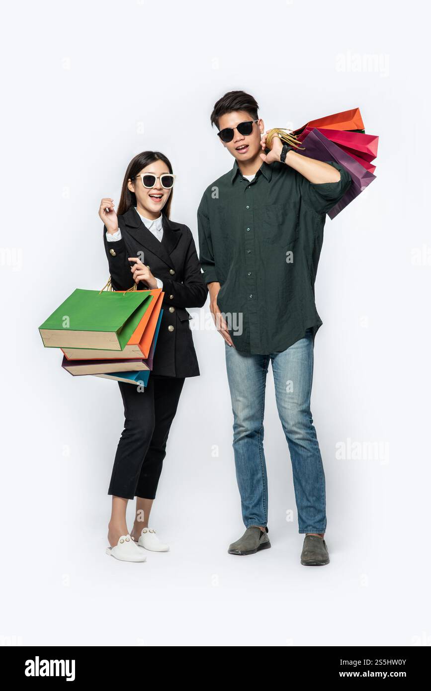 Une paire d'hommes et de femmes portaient des lunettes et transportaient beaucoup de sacs en papier pour faire du shopping. Banque D'Images