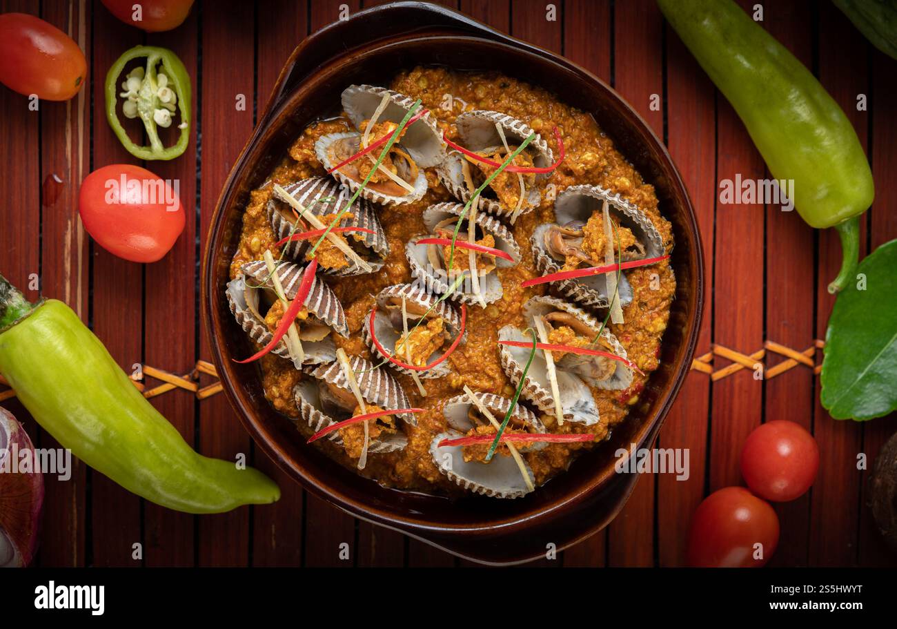 Coques sautées dans de la poudre de curry avec des poivrons et des tomates. Banque D'Images