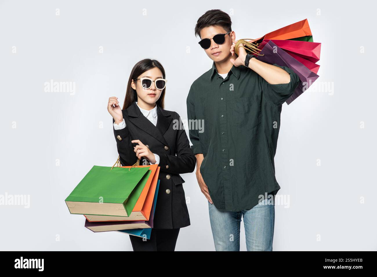 Une paire d'hommes et de femmes portaient des lunettes et transportaient beaucoup de sacs en papier pour faire du shopping. Banque D'Images
