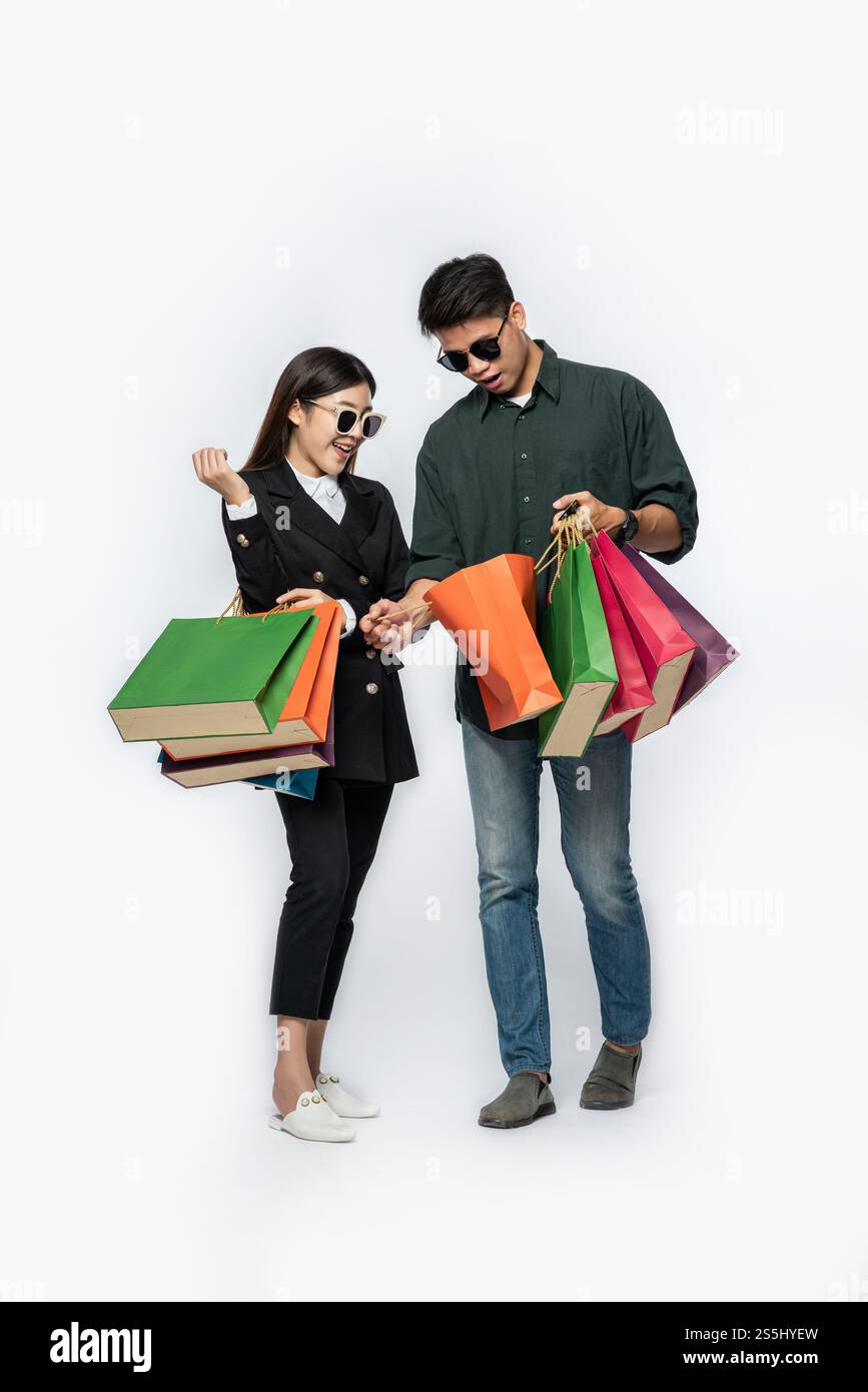 Une paire d'hommes et de femmes portaient des lunettes et transportaient beaucoup de sacs en papier pour faire du shopping. Banque D'Images