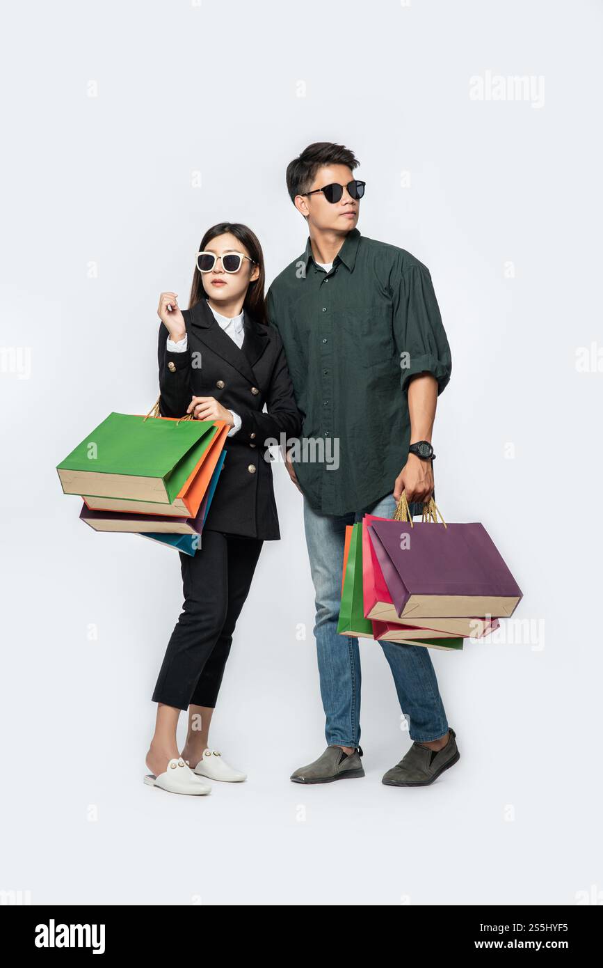 Une paire d'hommes et de femmes portaient des lunettes et transportaient beaucoup de sacs en papier pour faire du shopping. Banque D'Images