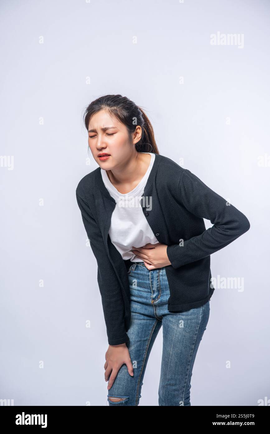 Une femme debout avec un mal de ventre et appuie sa main sur son ventre. Banque D'Images