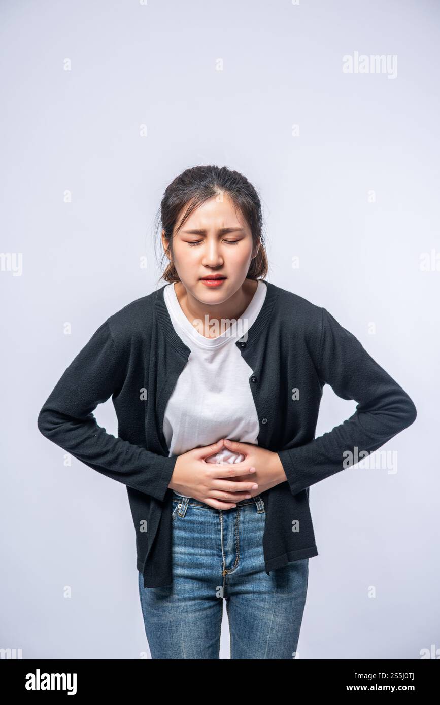 Une femme debout avec un mal de ventre et appuie sa main sur son ventre. Banque D'Images