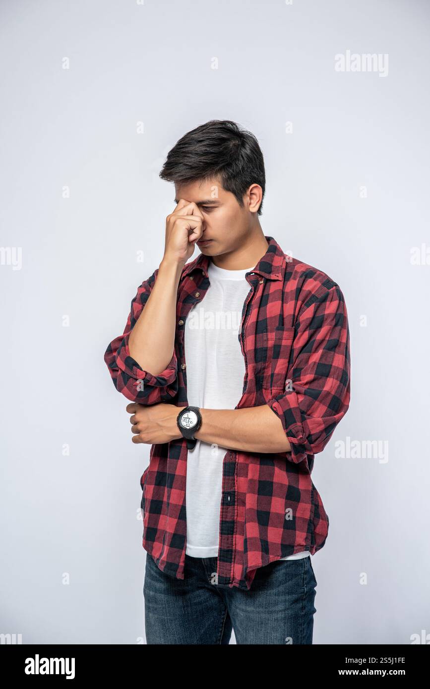 Un homme avec un mal de tête migraineux tenant sa main dans le nez Banque D'Images