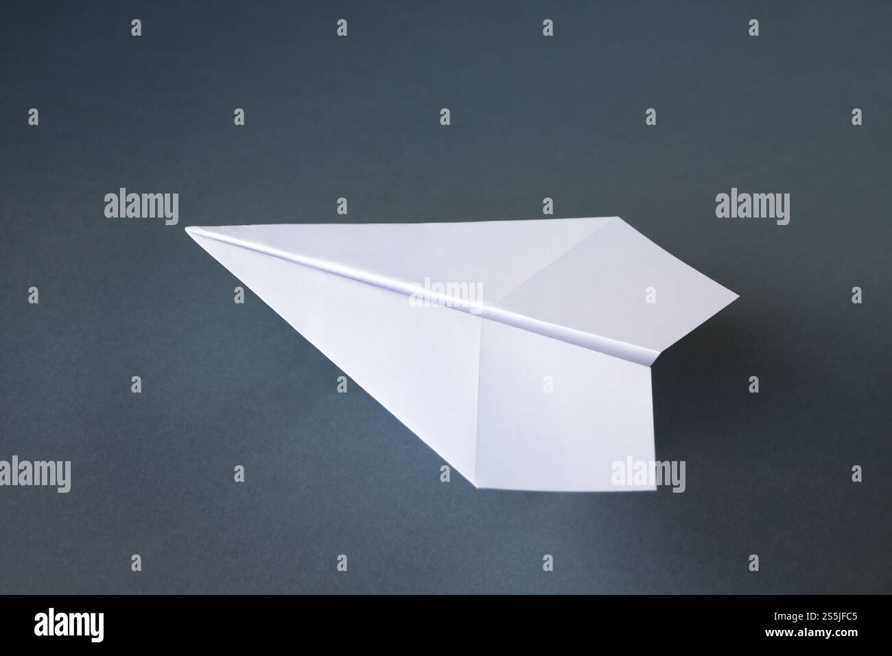 Origami avion en papier blanc isolé sur un fond gris vierge. Origami avion en papier blanc isolé sur un fond gris Banque D'Images