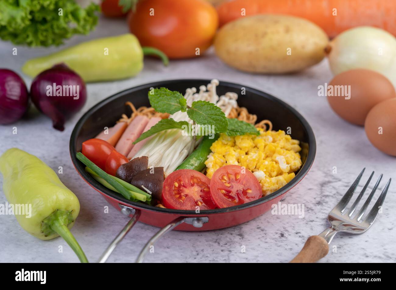 Nouilles sautées qui combinent maïs, champignon doré, tomate, saucisse, edamame et ciboule dans une poêle. Banque D'Images
