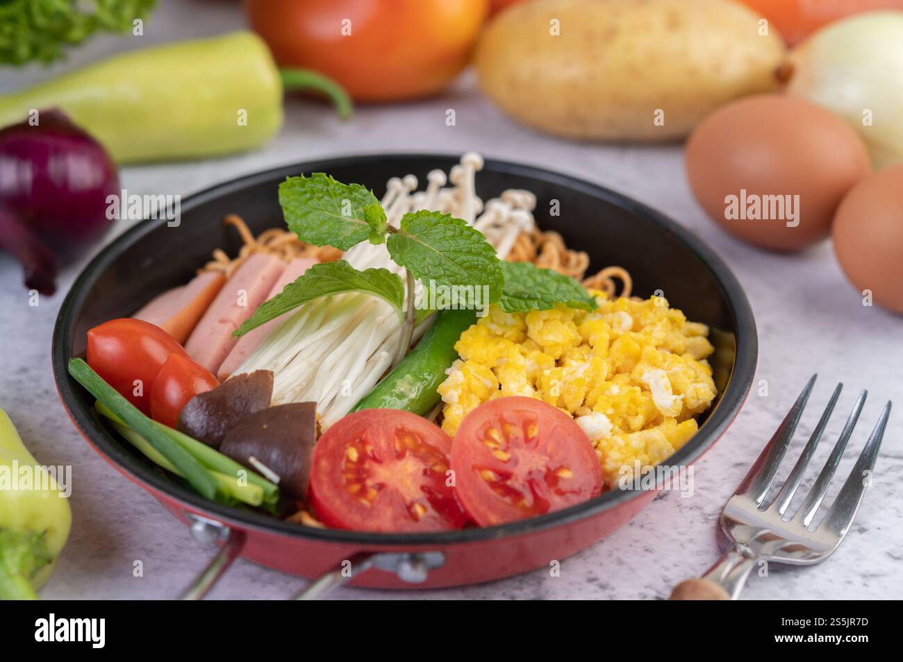 Nouilles sautées qui combinent maïs, champignon doré, tomate, saucisse, edamame et ciboule dans une poêle. Banque D'Images