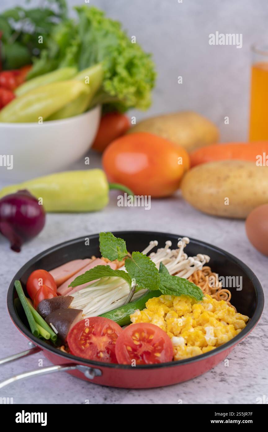 Nouilles sautées qui combinent maïs, champignon doré, tomate, saucisse, edamame et ciboule dans une poêle. Banque D'Images
