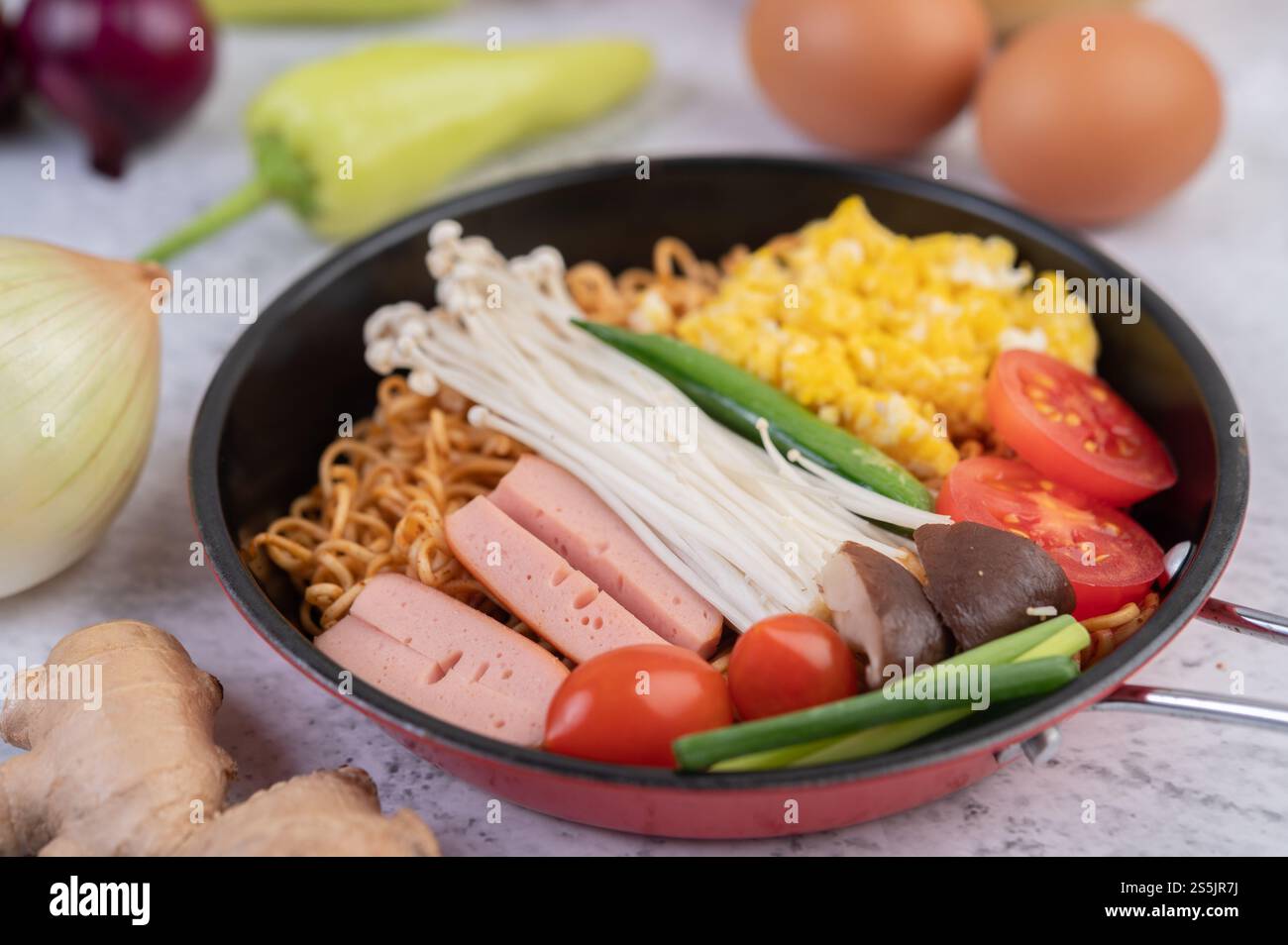 Nouilles sautées qui combinent maïs, champignon doré, tomate, saucisse, edamame et ciboule dans une poêle. Banque D'Images