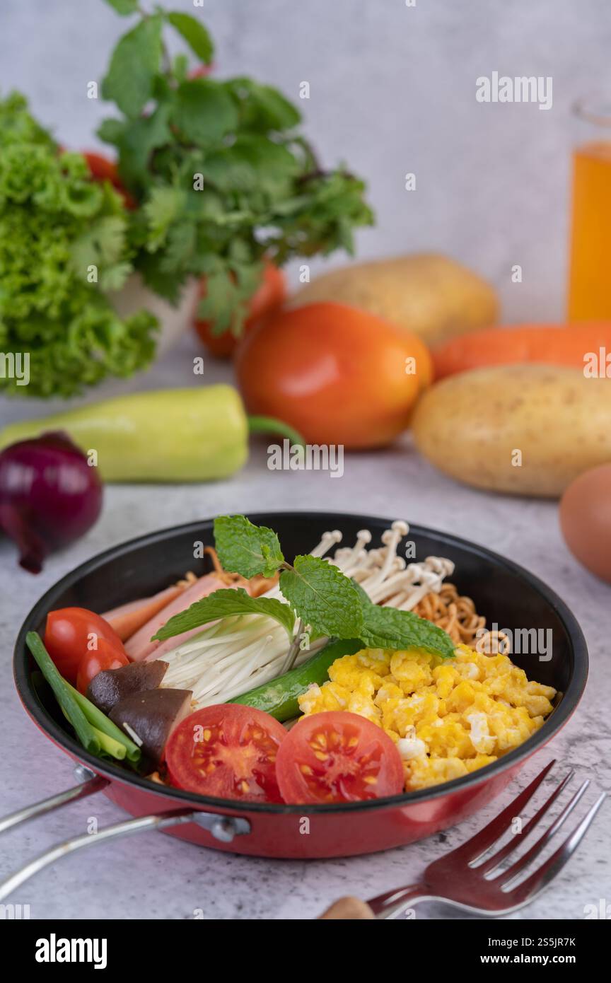 Nouilles sautées qui combinent maïs, champignon doré, tomate, saucisse, edamame et ciboule dans une poêle. Banque D'Images