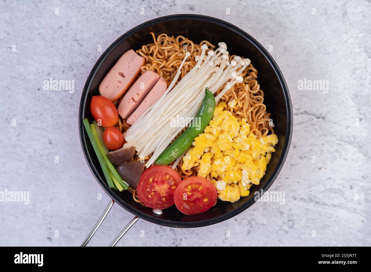 Nouilles sautées qui combinent maïs, champignon doré, tomate, saucisse, edamame et ciboule dans une poêle. Banque D'Images