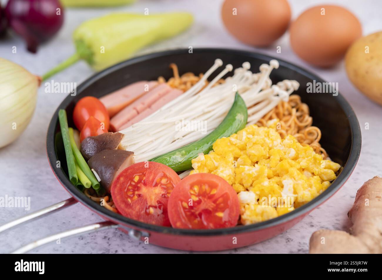 Nouilles sautées qui combinent maïs, champignon doré, tomate, saucisse, edamame et ciboule dans une poêle. Banque D'Images