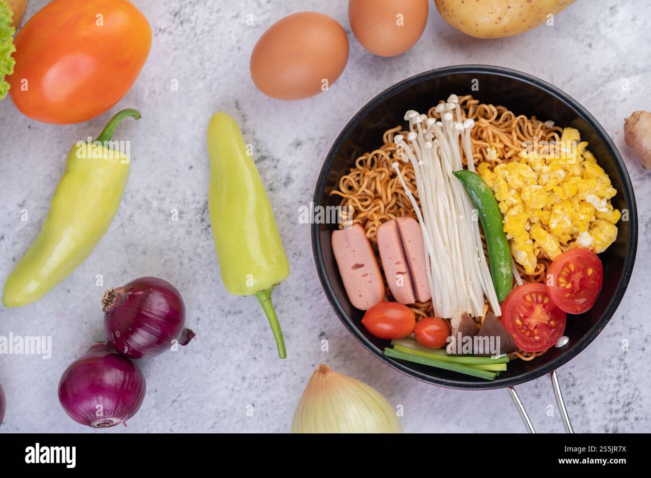 Nouilles sautées qui combinent maïs, champignon doré, tomate, saucisse, edamame et ciboule dans une poêle. Banque D'Images