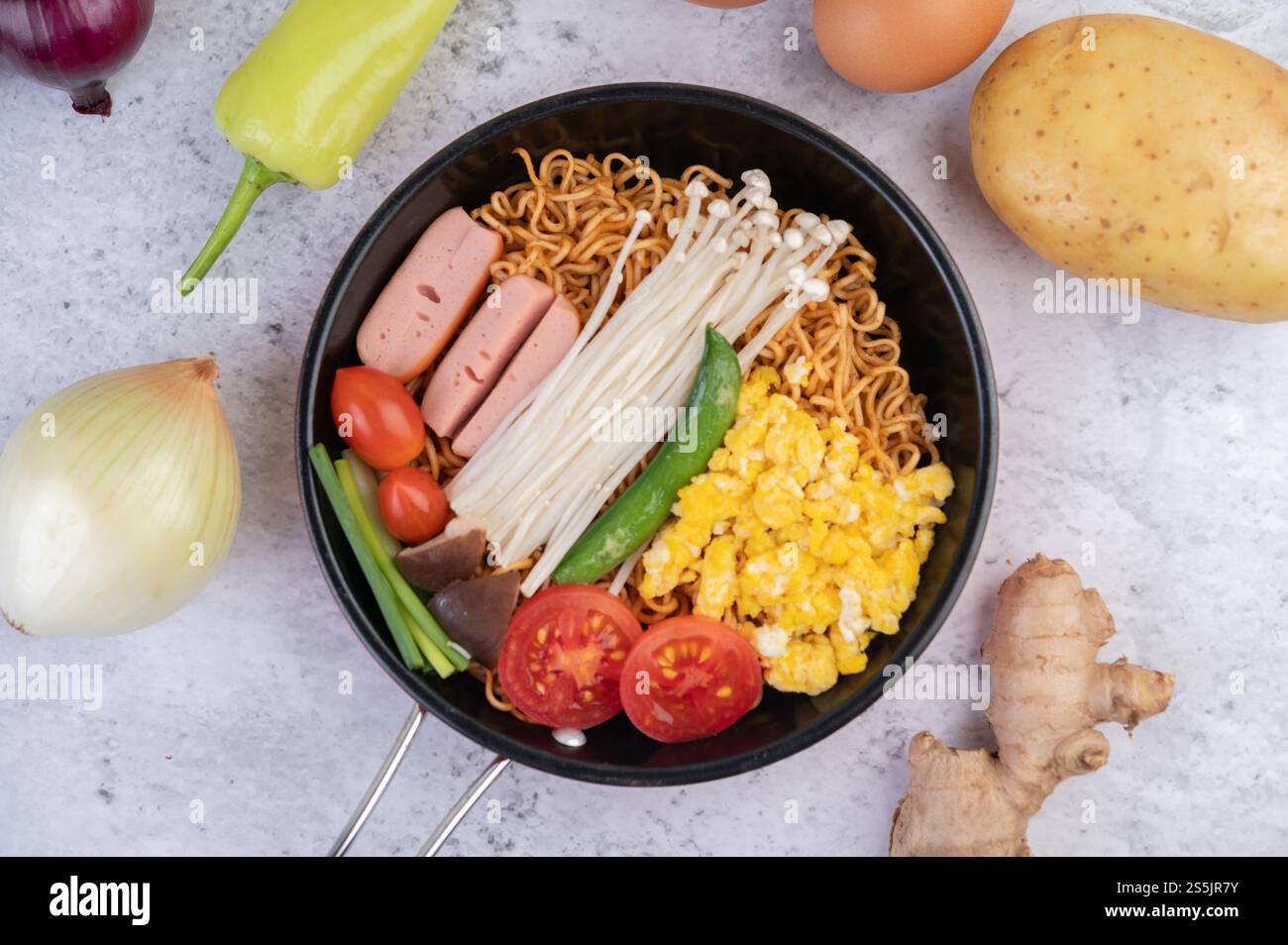 Nouilles sautées qui combinent maïs, champignon doré, tomate, saucisse, edamame et ciboule dans une poêle. Banque D'Images