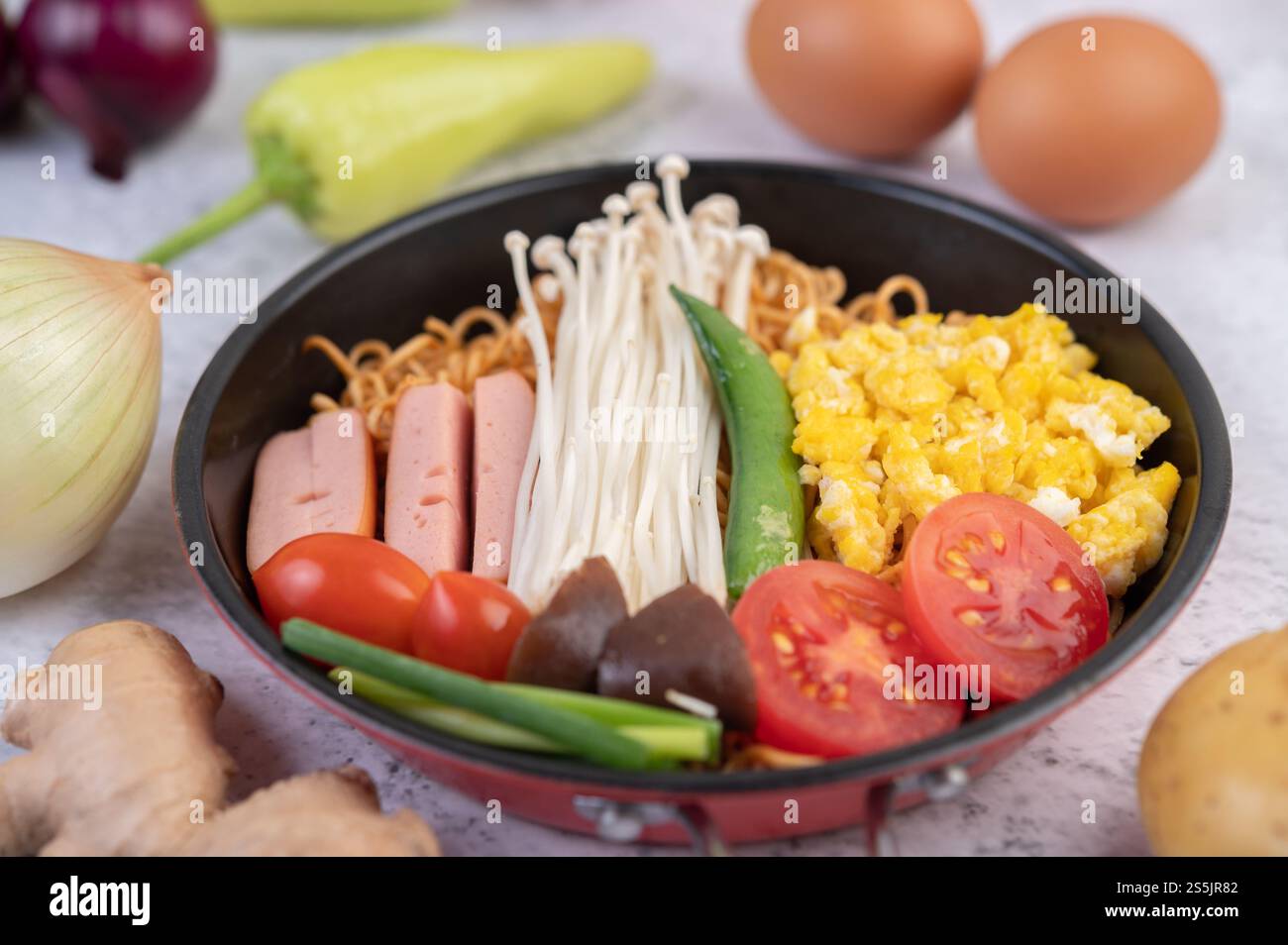 Nouilles sautées qui combinent maïs, champignon doré, tomate, saucisse, edamame et ciboule dans une poêle. Banque D'Images