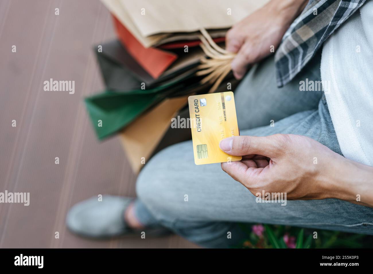 Sélectionnez Focus carte de crédit dans la main de jeune bel homme dans le masque, il tenant le sac de papier et montrer la carte de crédit sur l'escalier du centre commercial, New normal Banque D'Images