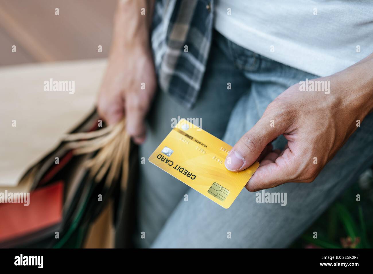 Sélectionnez Focus carte de crédit dans la main de jeune bel homme dans le masque, il tenant le sac de papier et montrer la carte de crédit sur l'escalier du centre commercial, New normal Banque D'Images