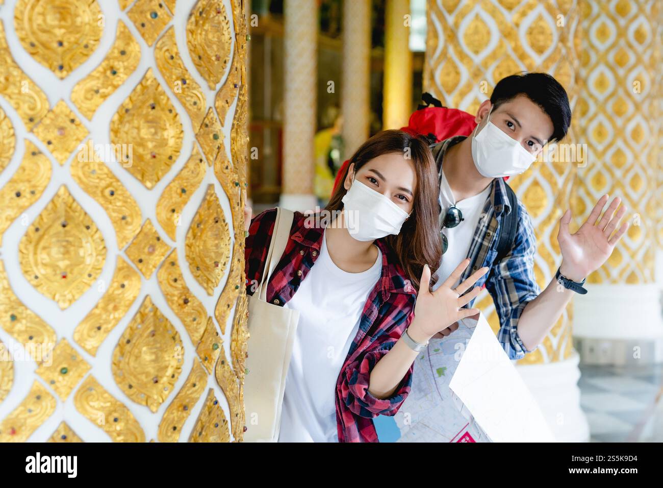 Portrait jeune couple de routards asiatiques debout et tiennent la carte de papier à la main au beau temple thaïlandais, ils agitent la main à saluer et regarder Banque D'Images