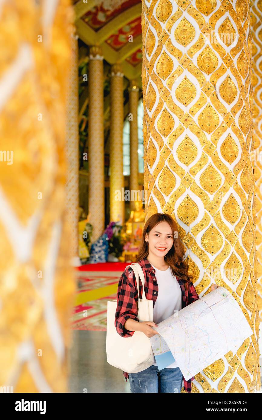 Portrait jeune femme de routard asiatique debout et tenir la carte de papier à la main au beau temple thaïlandais, elle regardant la caméra Banque D'Images