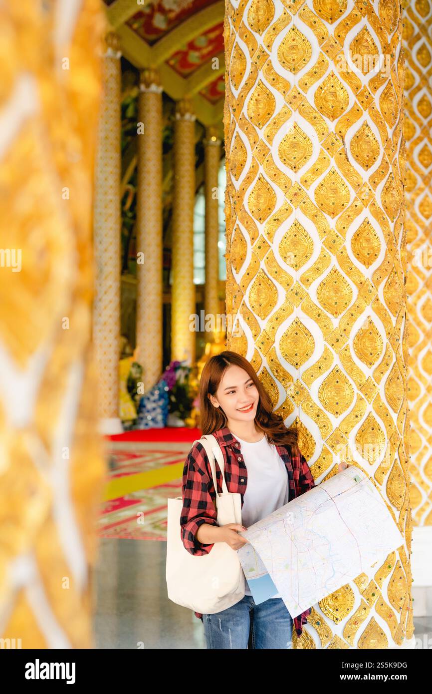 Portrait jeune femme de routard asiatique dans le masque debout et tenir la carte de papier à la main au beau temple thaïlandais, elle regardant loin Banque D'Images