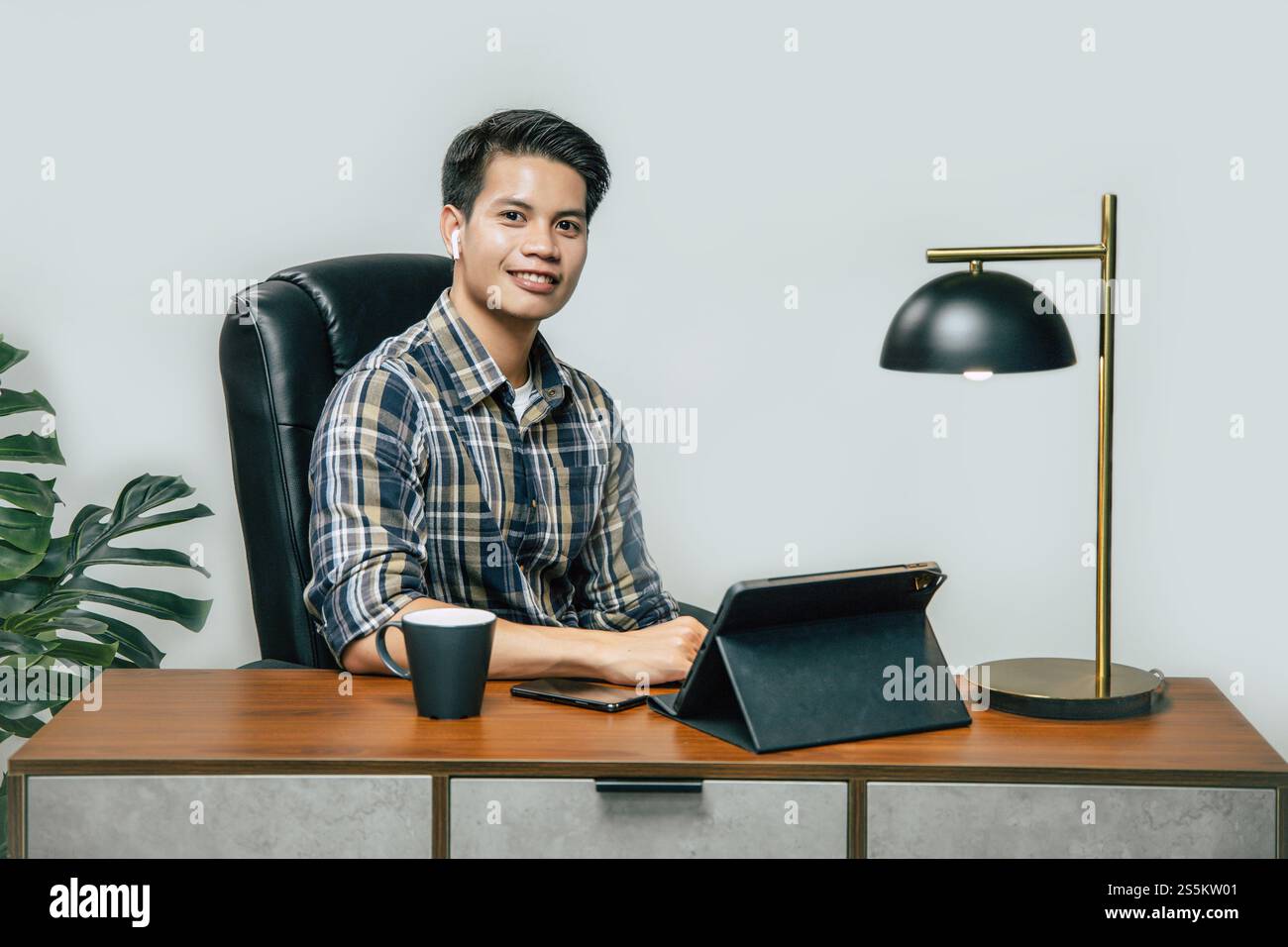 Heureusement jeune homme beau avec une nouvelle normalité, rester à la maison et travailler à partir de la maison sur tablette numérique et utiliser smartphone pendant l'auto-isolement et Banque D'Images
