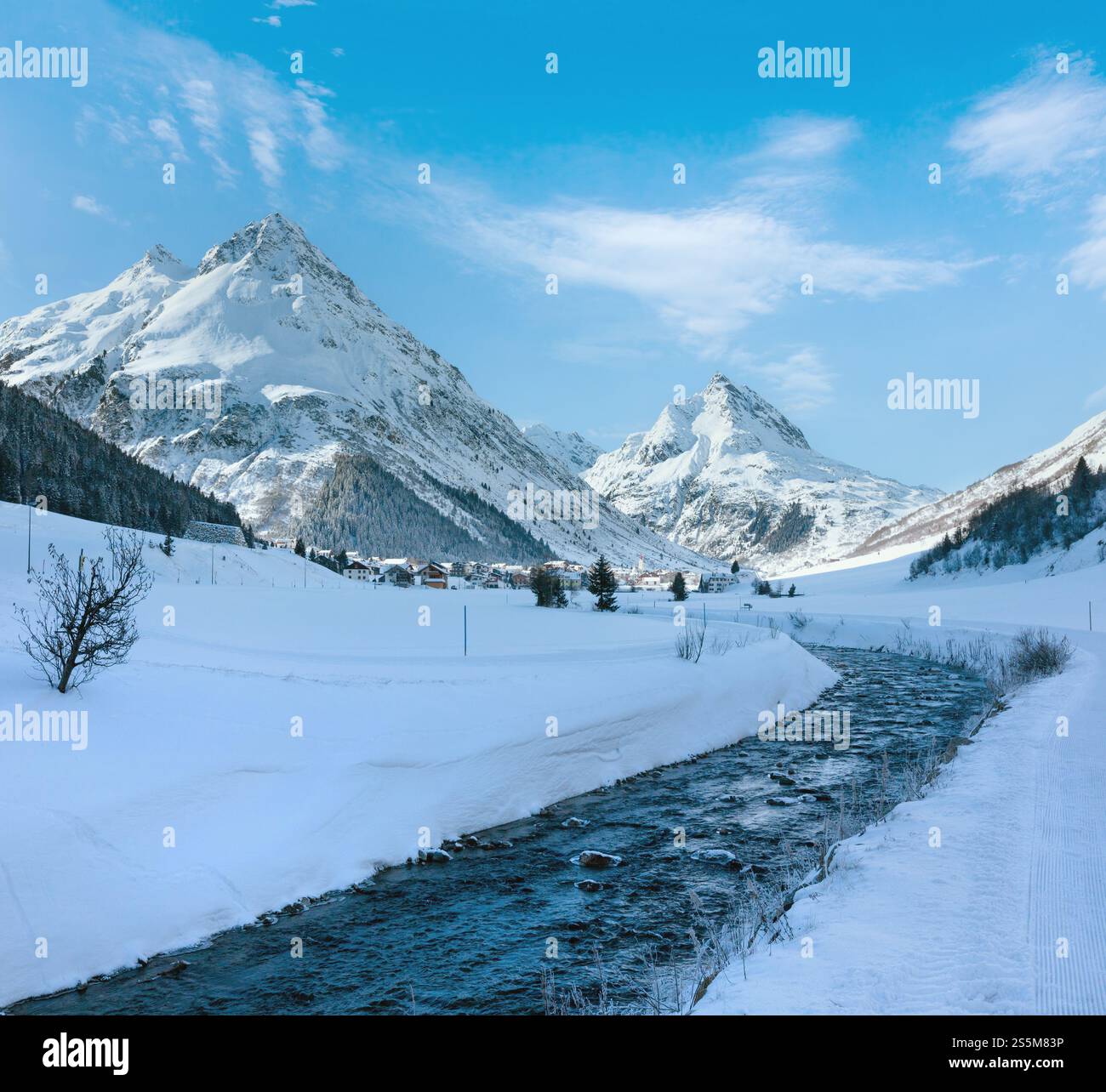 Vue sur les cours d'eau de montagne en hiver et village dans la vallée (Autriche). Banque D'Images